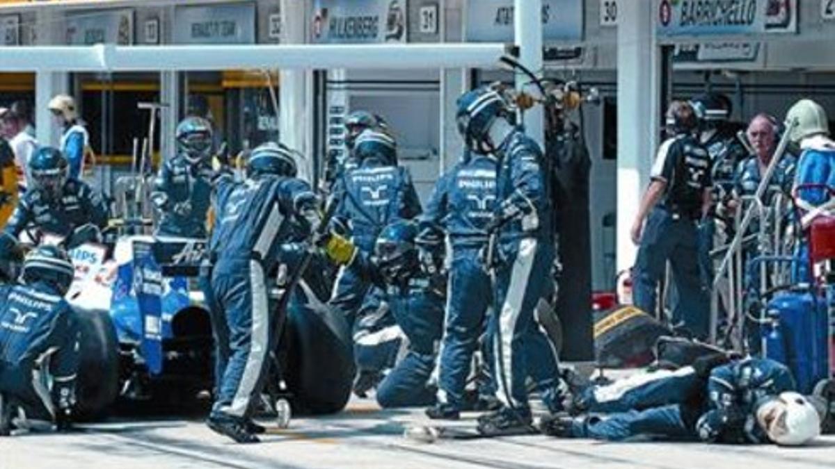 Un mecánico cae abatido por el golpe de la rueda del coche de Rosberg que vuela sobre el sobre el resto.