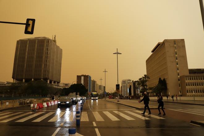 La calima deja el cielo de Málaga de color naranja y los coches llenos de polvo.