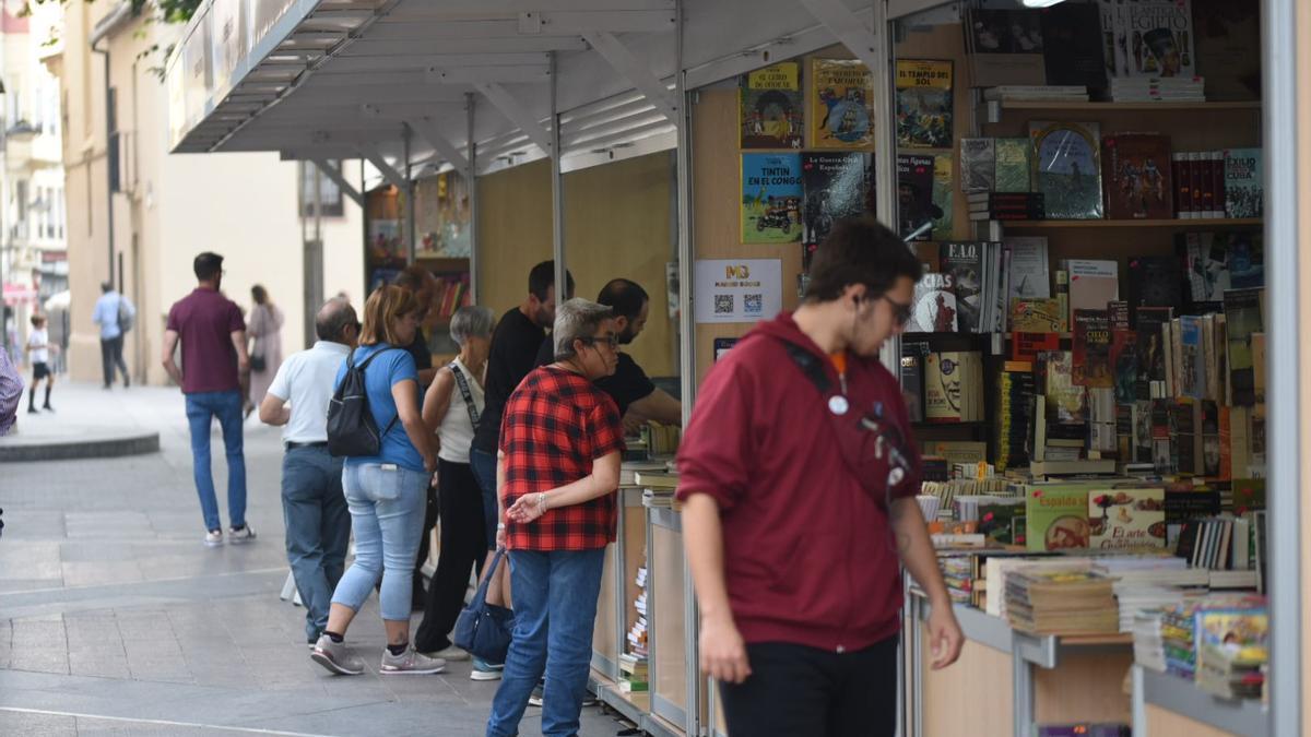 Varios ciudadanos observan los libros que ofrece la feria.