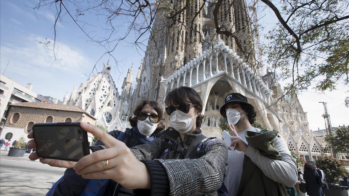 Unos turistas se hacen fotos en la Sagrada Família, cerrada al público debido al coronavirus.