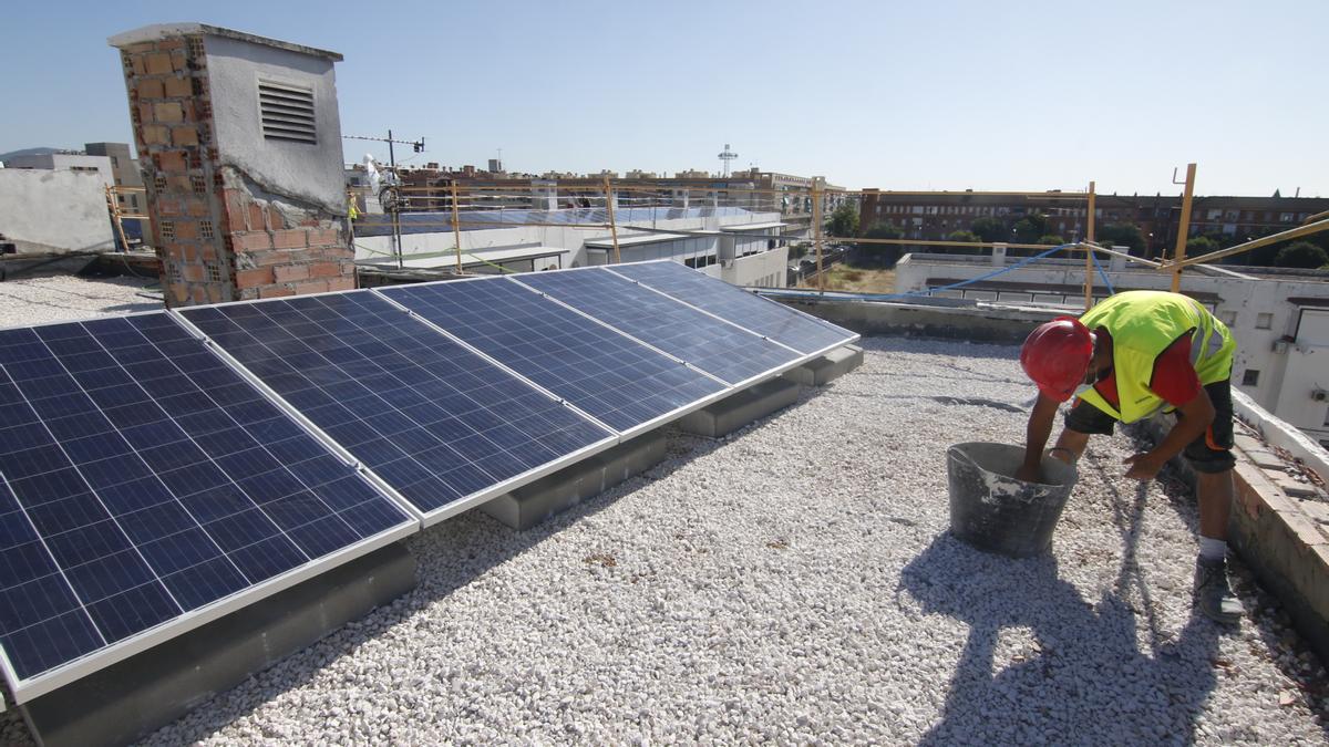 Un operario trabaja en la instalación de paneles solares en la cubierta de un edificio.
