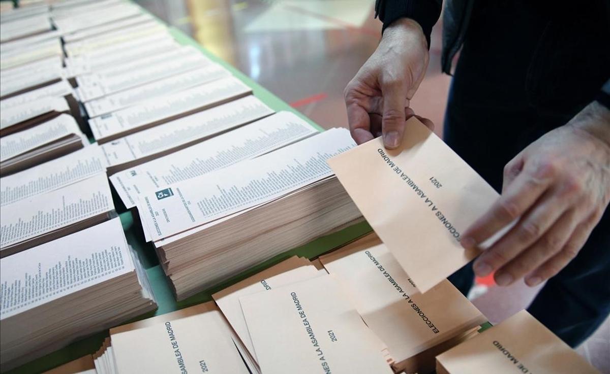 Un miembro de la mesa electoral coloca una mesa con papeletas momentos antes de la apertura del colegio Roma de Madrid.