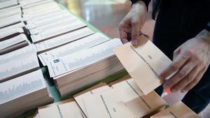 Un miembro de la mesa electoral coloca una mesa con papeletas momentos antes de la apertura del colegio Roma de Madrid.