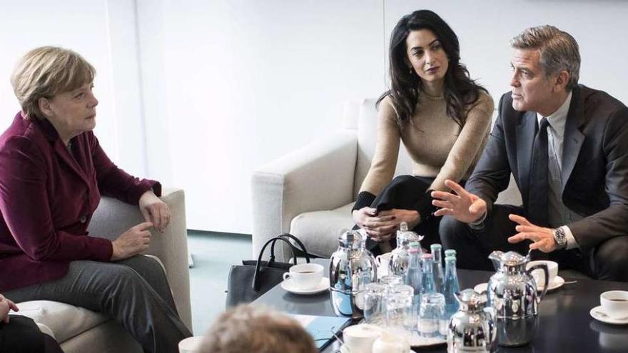 George Clooney y su esposa, Amal, durante la entrevista con la canciller alemana Angela Merkel, ayer en Berlín. // Reuters