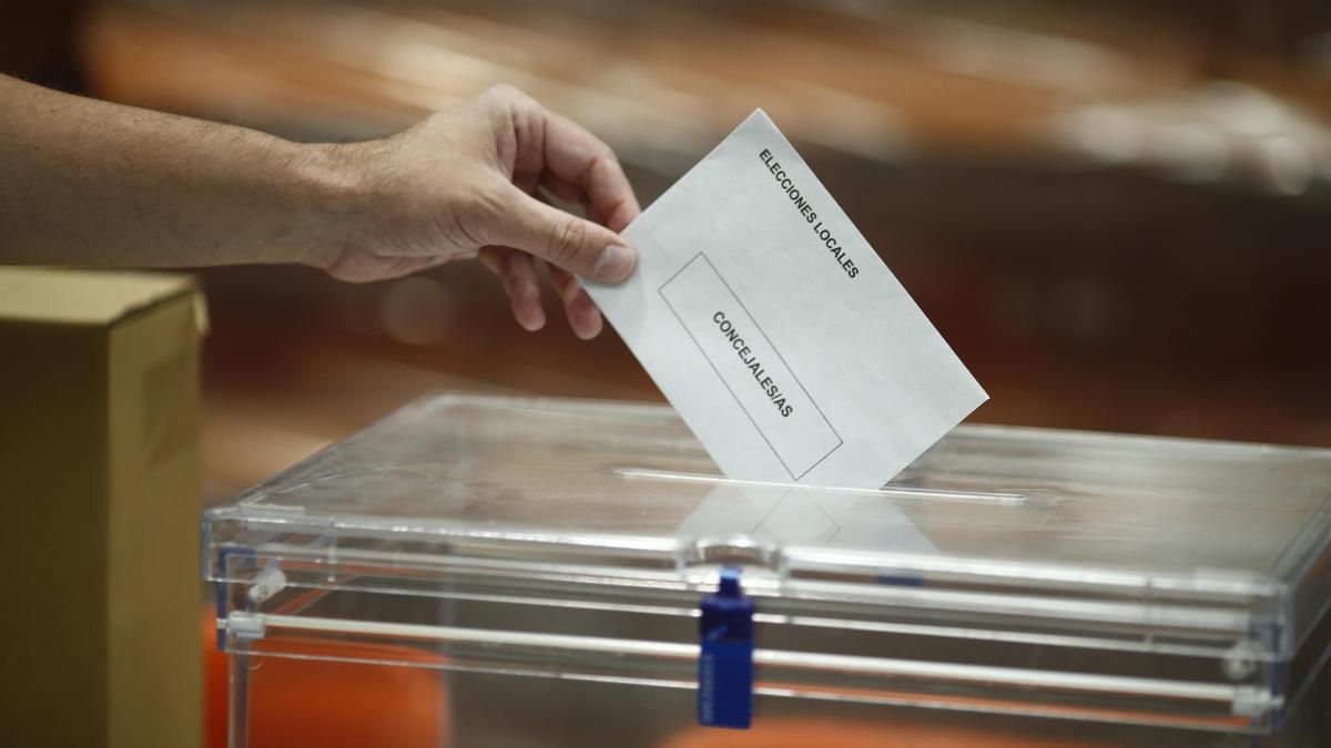 Una persona introduce un voto en una urna.