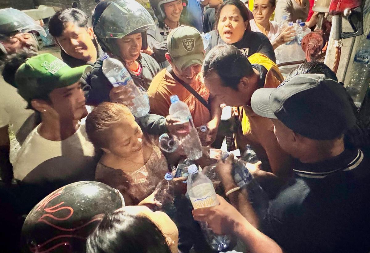 Decenas de personas rodean, en Bali, a un empleado de una gasolinera que rellena hasta botellas de plástico con combustible.