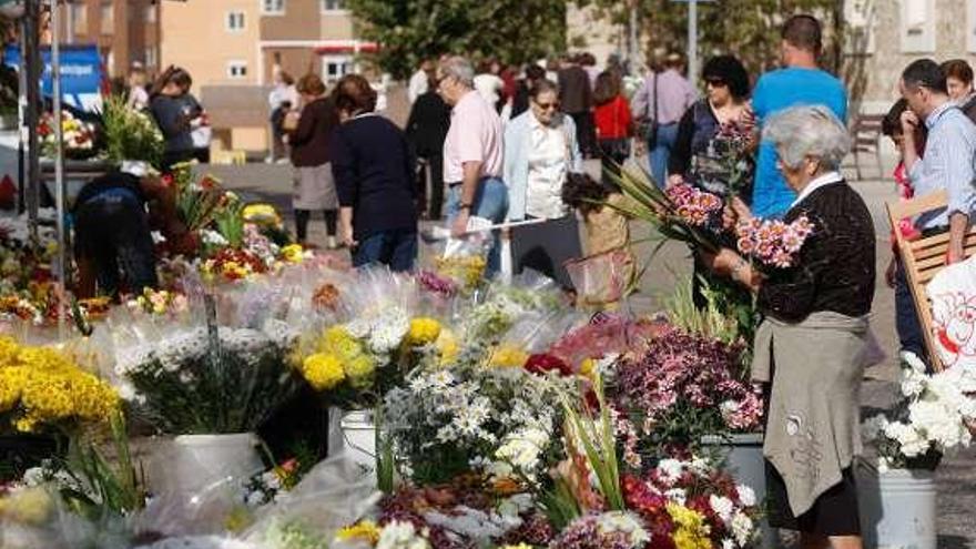 Tres mujeres visitan una sepultura repleta de flores.