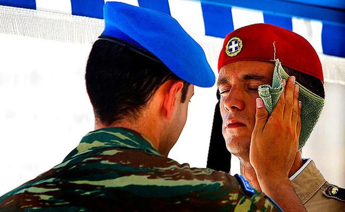 Un soldat passa un mocador humit per la cara d’un integrant de la guàrdia presidencial grega després de fer el canvi de guàrdia a la plaça Syntagma d’Atenes.