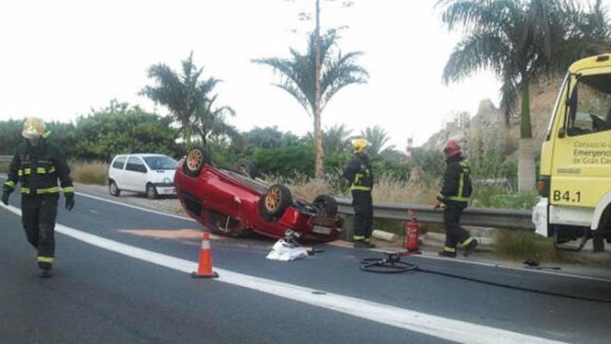 Dos bomberos, junto al coche que volcó en la entrada de Taurito. i LP/DLP