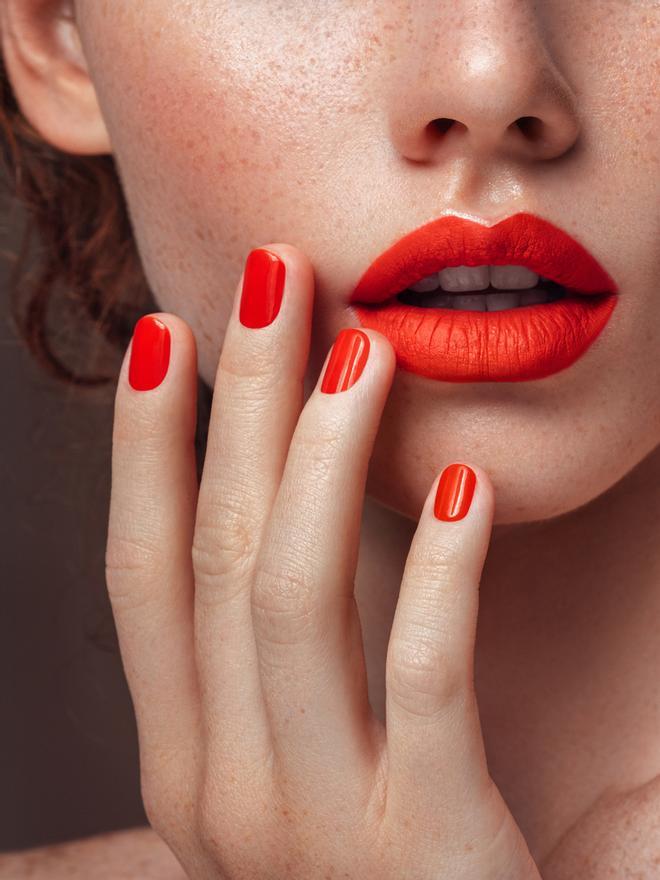 Mujer con manicura y labios en rojo