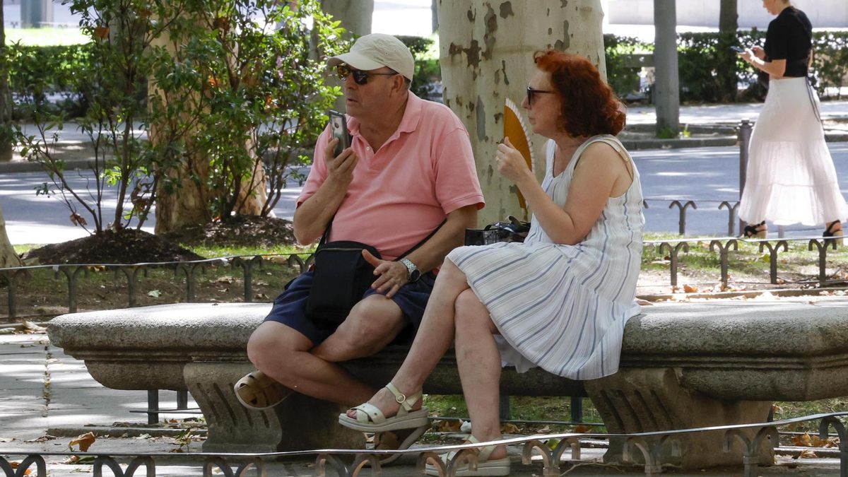 Dos personas se protegen del calor en un parque de Madrid.