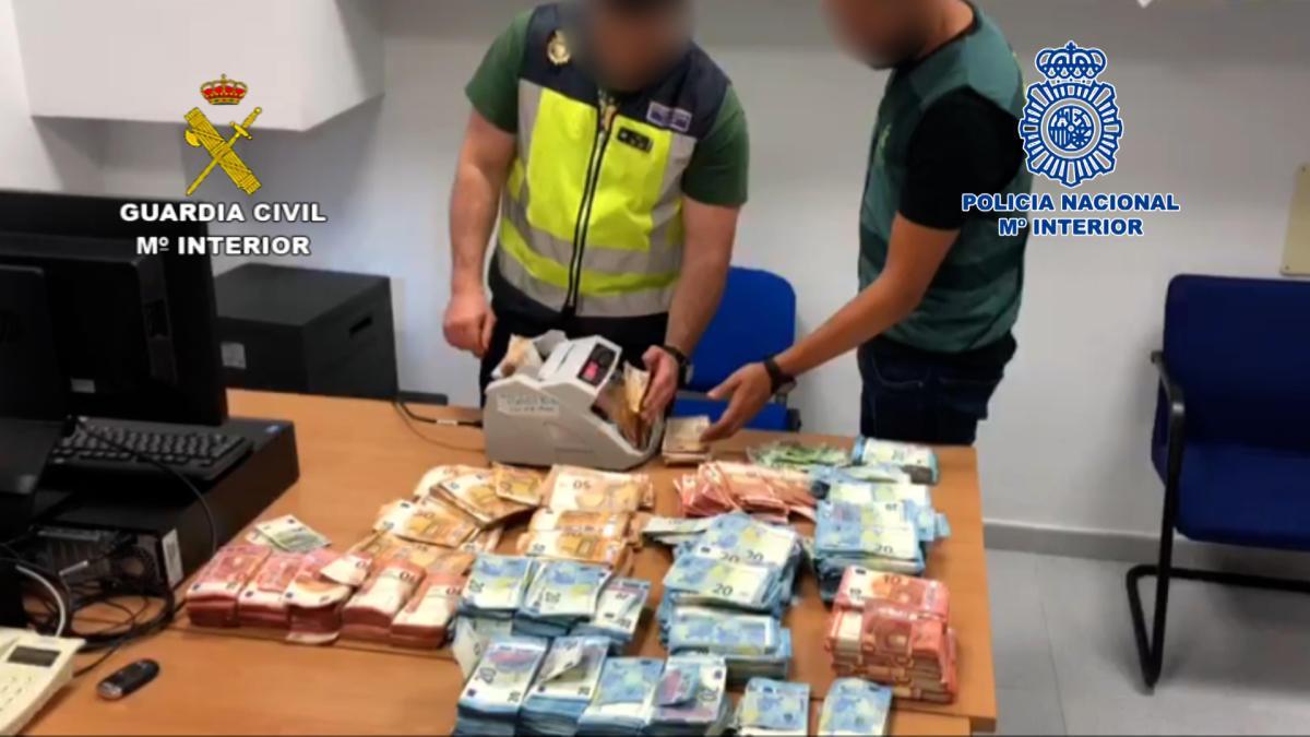 Dos agentes cuentan el dinero incautado a la red de narcos durante la operación conjunta.