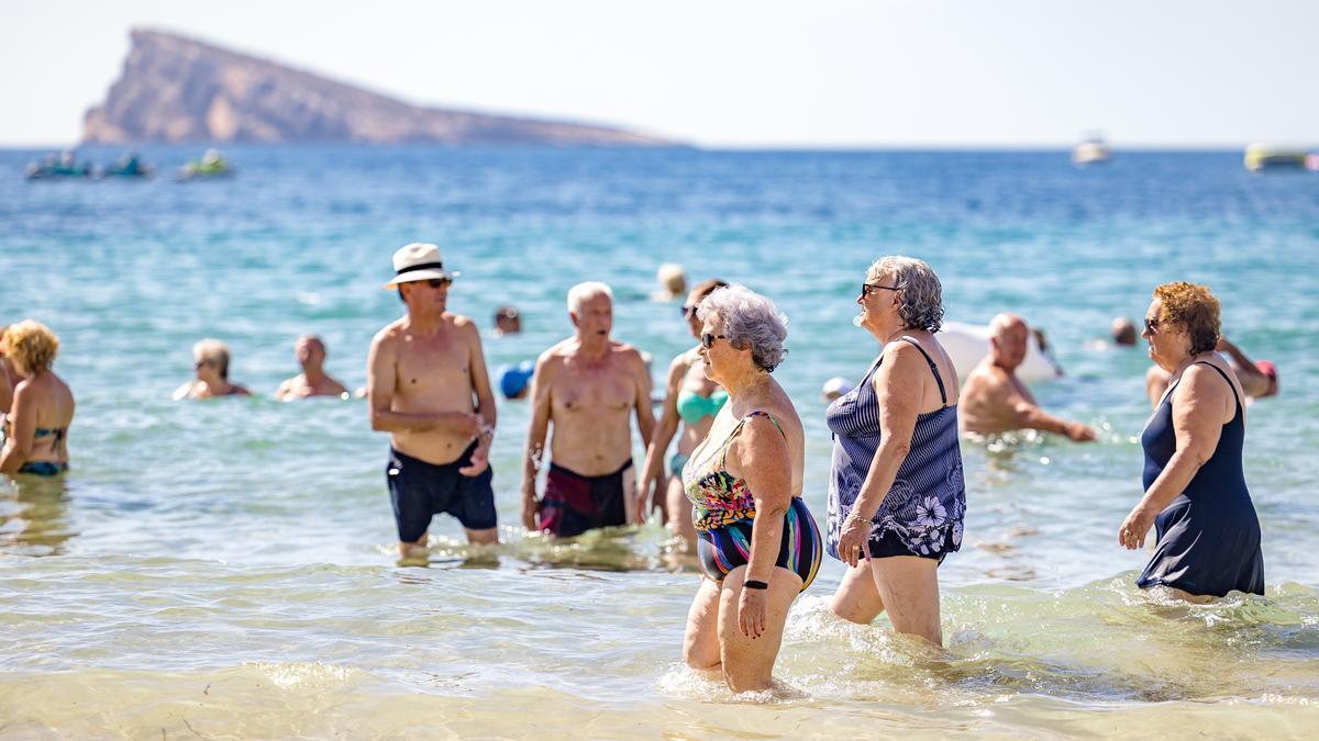 Personas mayores toman el baño en la playa de Benidorm, uno de los destinos estrella para los jubilados que viajan con el Imserso.