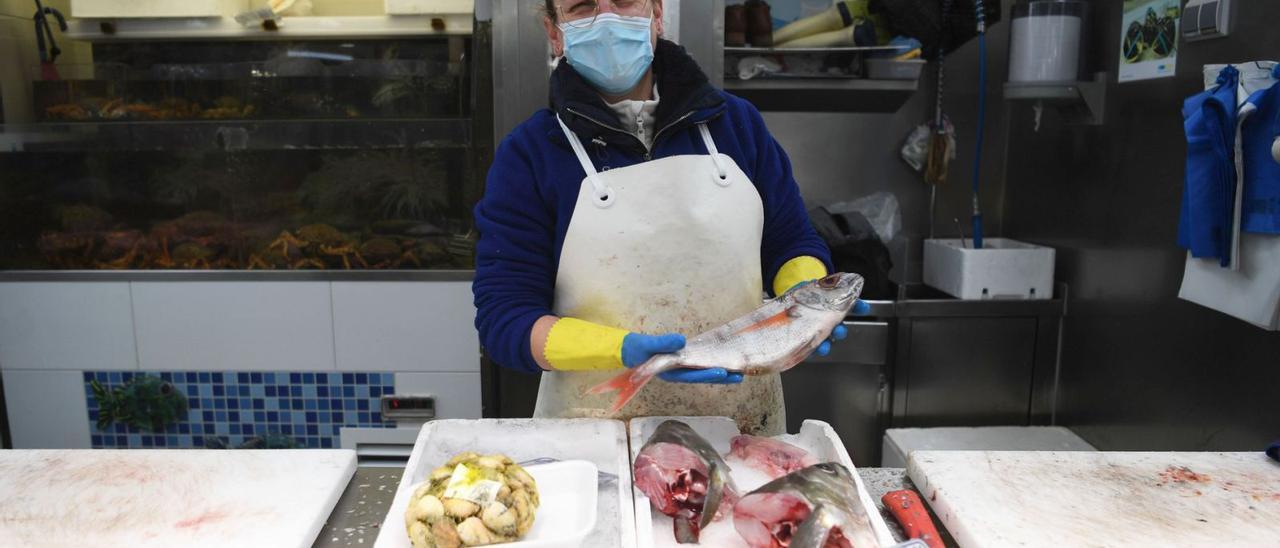 Trabajadora del puesto Mariscos Dory, ayer, con un besugo en la mano.   | // CARLOS PARDELLAS