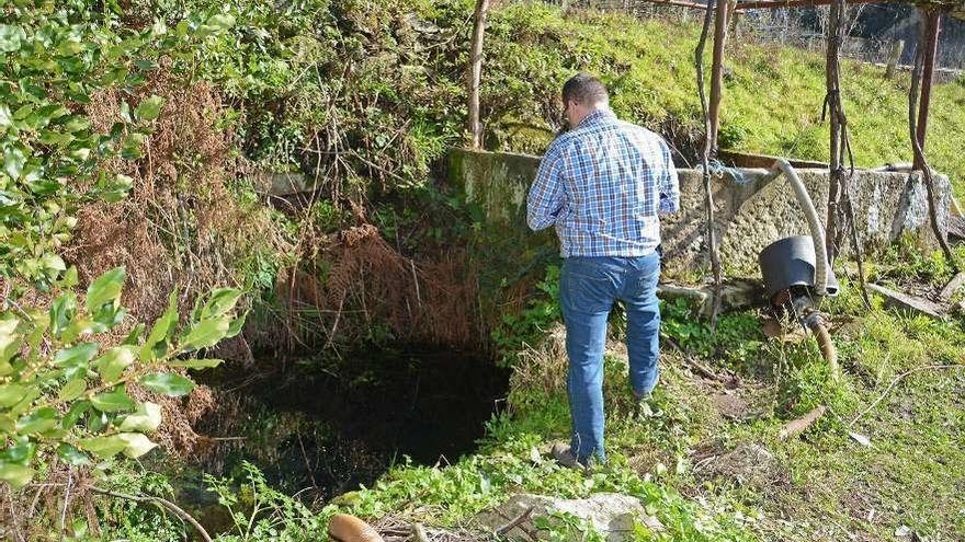 Un hombre mira el pozo de agua en el que se encontró el cadáver de esta octogenaria ayer. // G. Santos