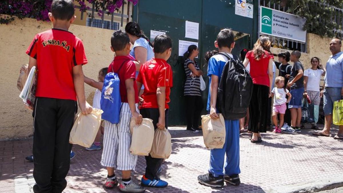 Varios niños de un centro escolar del barrio de La Palmilla, en Málaga, con las bolsas de comida.