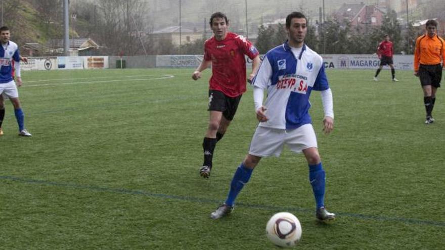 El delantero del Tuilla Omar controla el balón ante el central del Luarca Paul.