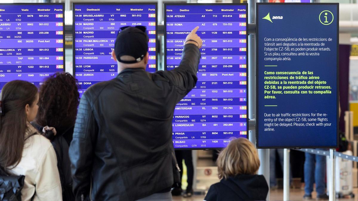 Pasajeros observan la pantalla de vuelos en el aeropuerto del Prat.