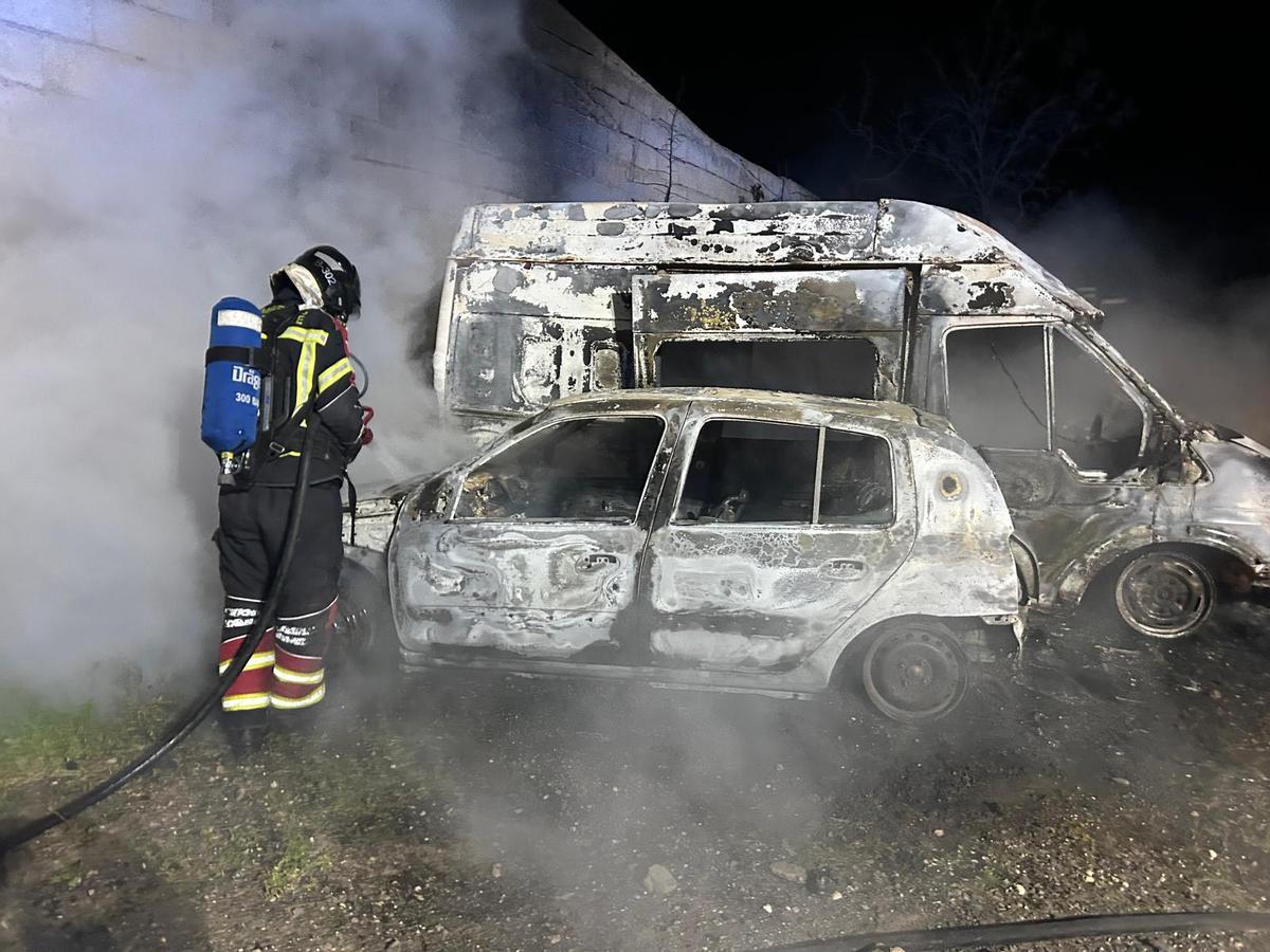 Un bombero apaga el fuego en dos vehículos en la noche del domingo en el Valle de Uga, en el municipio de Yaiza, en Lanzarote