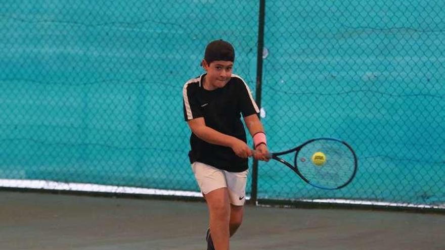 Un joven tenista devuelve una bola.