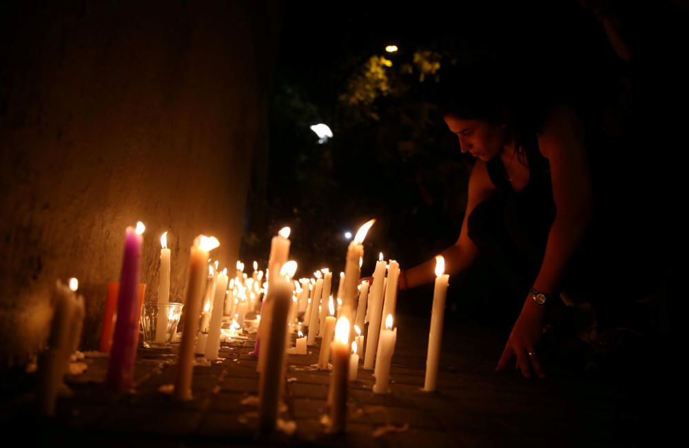 A woman places candles outside the Instituto ...