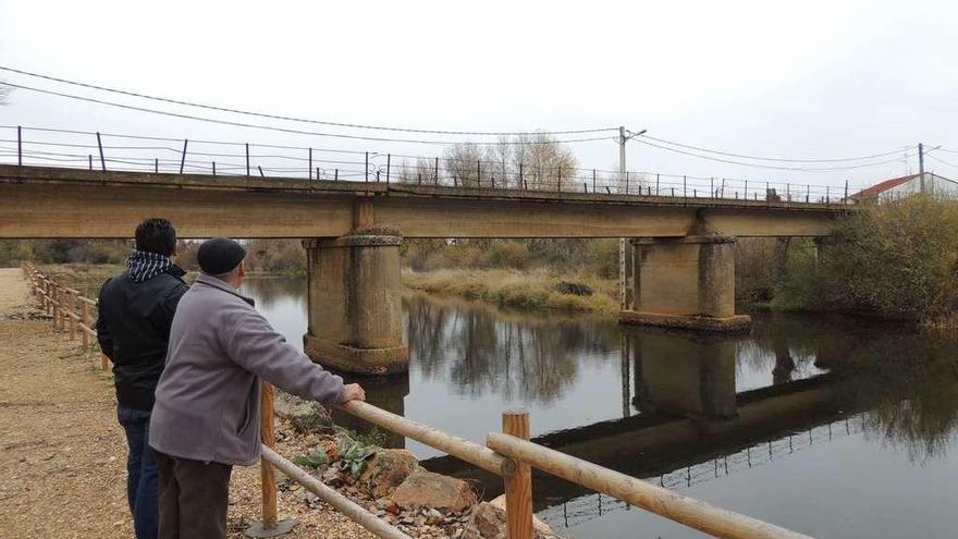 El alcalde de Villaferrueña Gregorio Martínez y un vecino observan el puente sobre el río Eria.