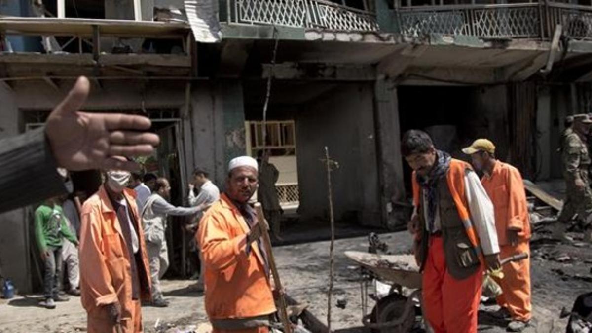 Un grupo de trabajadores locales limpian los destrozos causados por el atentado suicida, este jueves en Kabul.