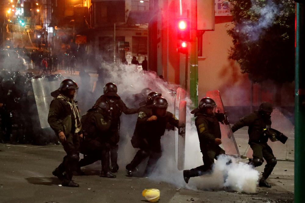 Riot police kick a tear gas canister thrown back ...