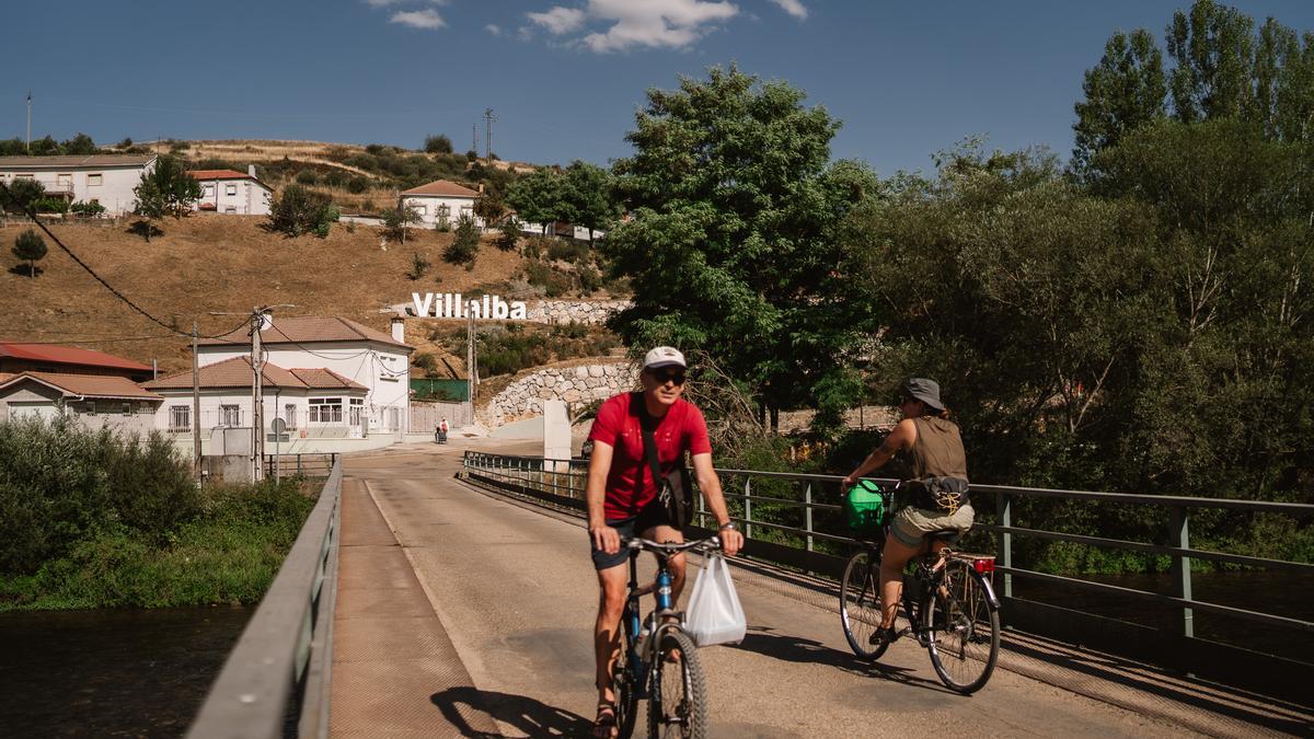 Varios vecinos atraviesan el puente que cruza el río Carrión, en Villalba de Guardo, el pueblo con el aire más puro de Europa.