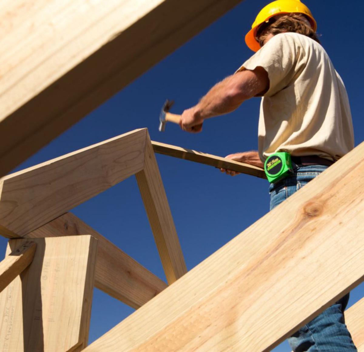 Un operario trabaja en una estructura de madera. | 