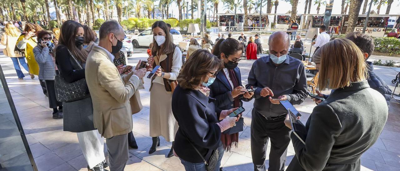 Un grupo de personas preparan el pasaporte covid para poder acceder a un establecimiento en Alicante