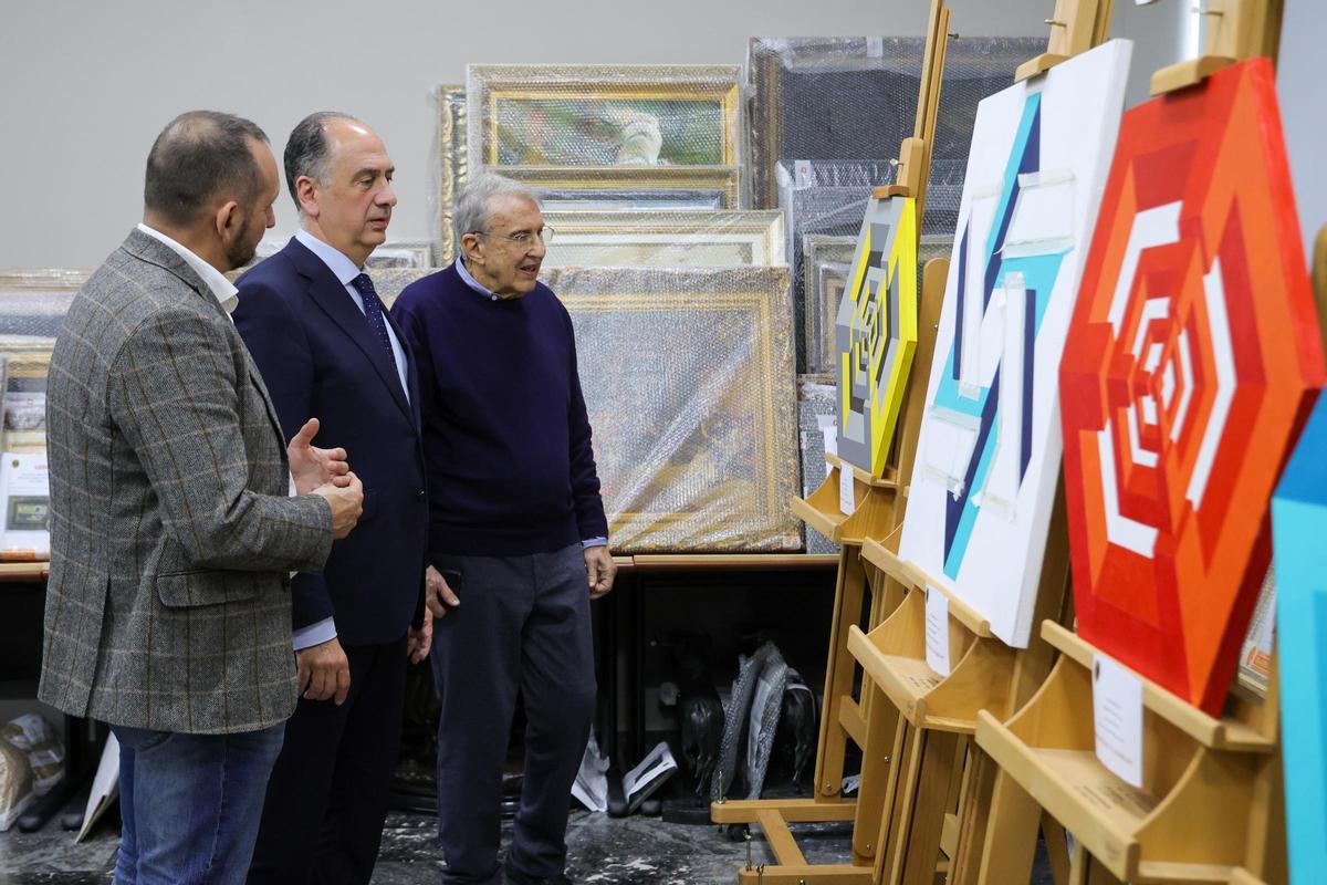 El conseller Juan Carlos Valderrrama y el artista José María Yturralde ante tres de las copias intervenidas.