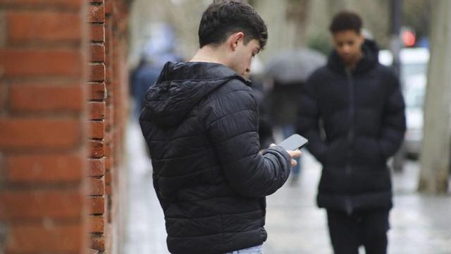 Un joven consulta sus redes sociales en medio de la calle.