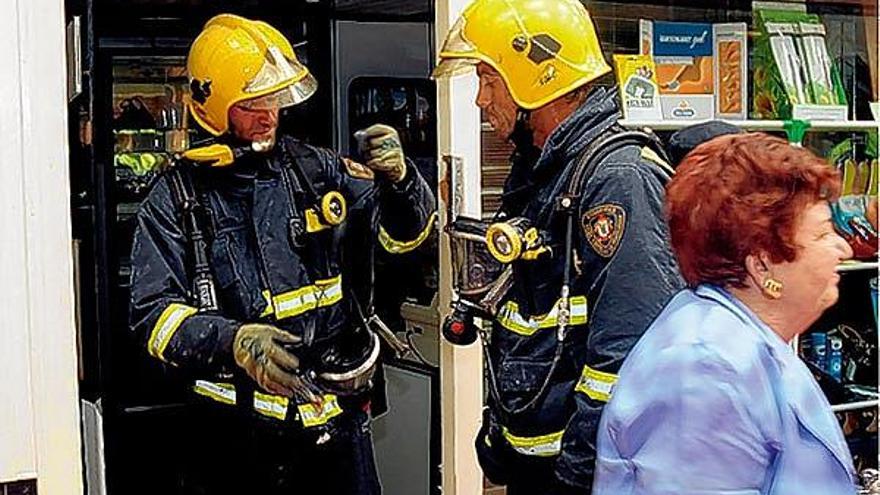 Los bomberos, ante el comercio en el que se produjo el fuego.