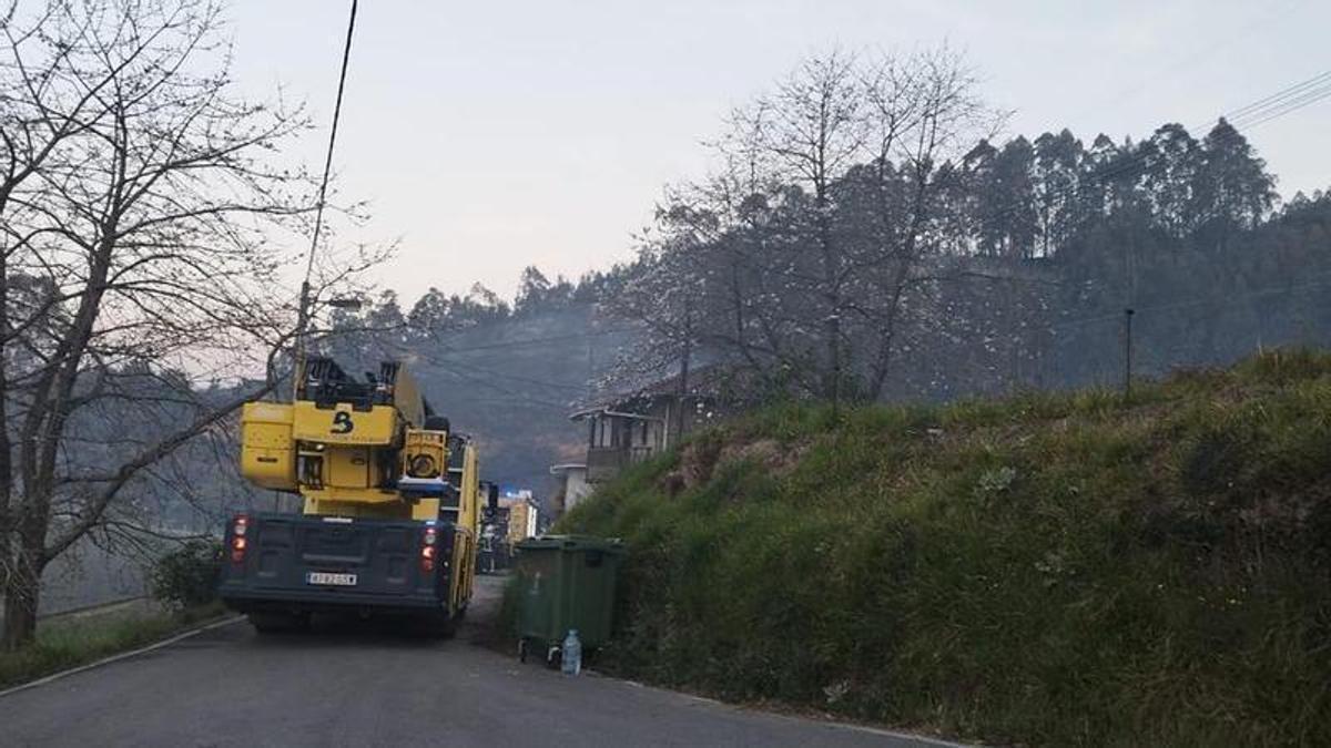 Camiones de bomberos que acudieron al incendio, con el monte quemado al fondo.