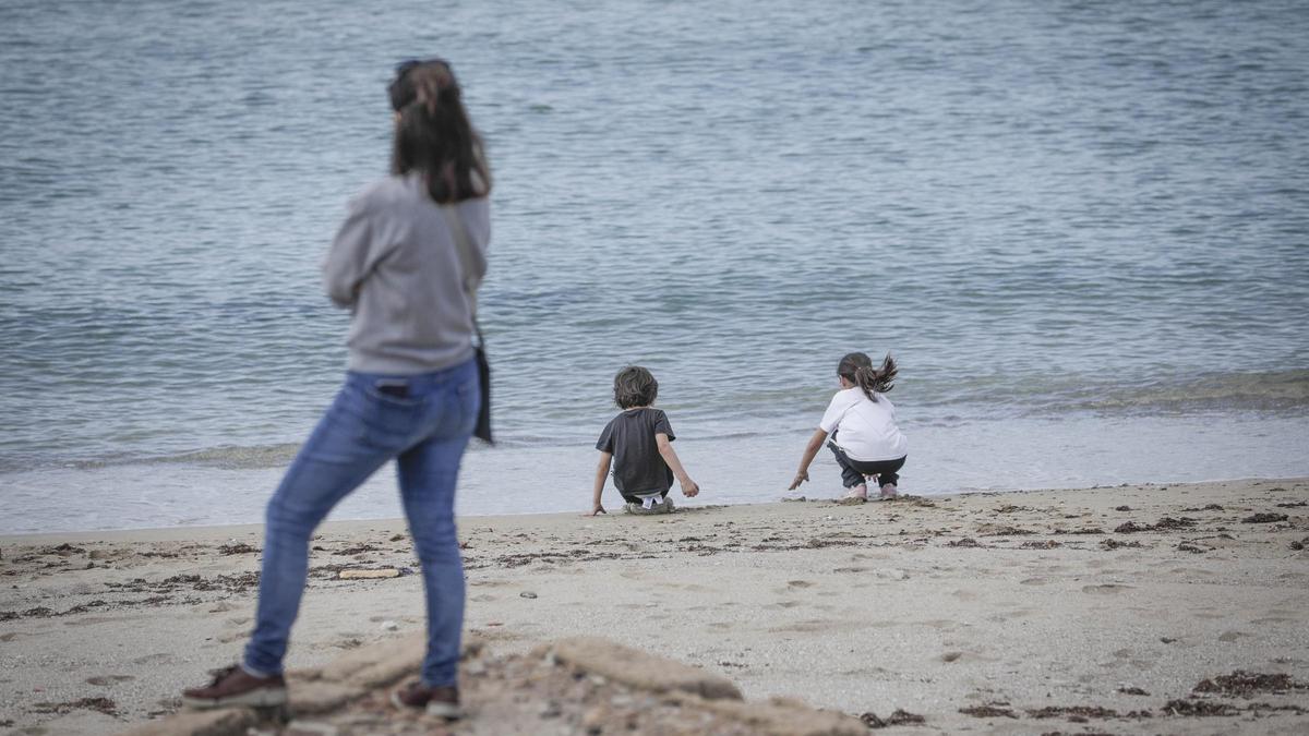 Una madre junto a sus hijos en la playa