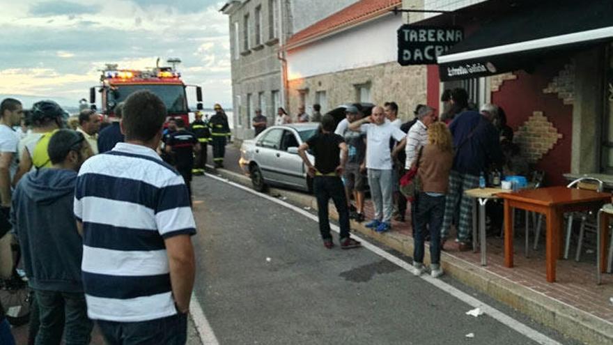 Vecinos y bomberos, en torno al coche que atropelló a las dos personas. // muñiz