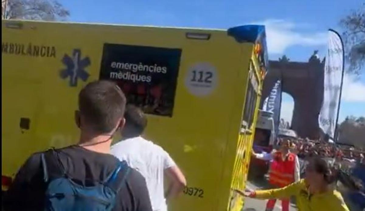 Servicios sanitarios intervienen durante la Maratón de Barcelona mientras varios corredores continúan la carrera ignorando el cordón de seguridad
