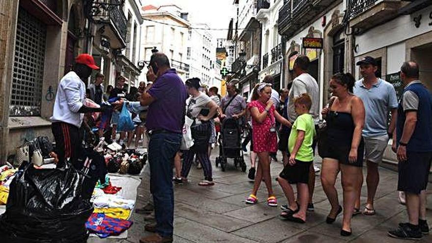 Varios turistas compran objetos a un mantero en la calle Real esta semana.