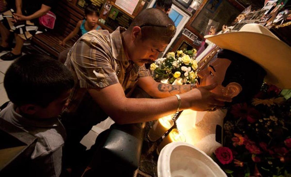 Un home agafa la cara d’una estàtua de San Jesús Malverve a la ciutat de Culiacán (nord-oest de Mèxic). D’acord amb la llegenda, a Jesús Malverde se’l considera una espècie de Robin Hood local, que als anys 1900 robava a les autoritats corruptes per llavors donar el que aconseguia als pobres. Malverde va ser assassinat el 3 de maig del 1909 i des d’aleshores els seus seguidors celebren cada any l’aniversari.