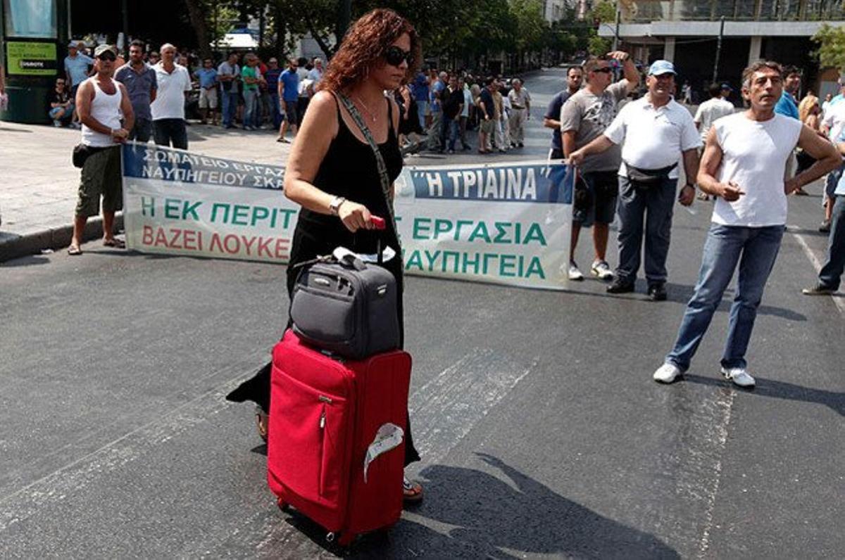 Una dona passa davant els treballadors de les drassanes, que han bloquejat un carrer cèntric durant una protesta a prop del Ministeri de Finances, a Atenes.