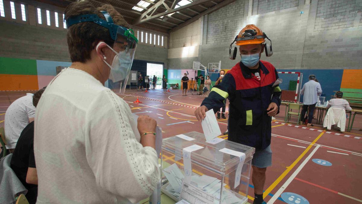 Un trabajador de Alcoa acude a votar con su uniforme de trabajo. // EP