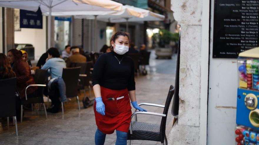 Una trabajadora de un restaurante se protege con mascarilla en el centro de València.