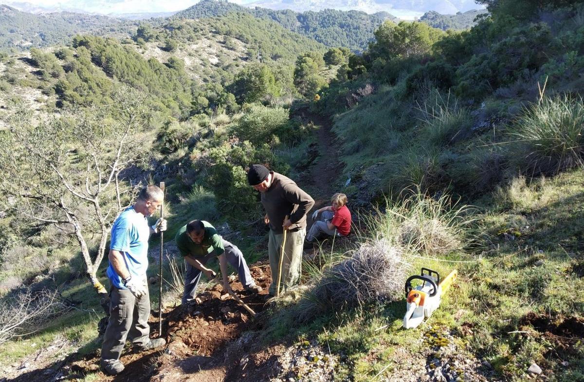 Un grupo de voluntarios trabaja, azada en mano, en plena sierra. | JOSEMI SEPÚLVEDA