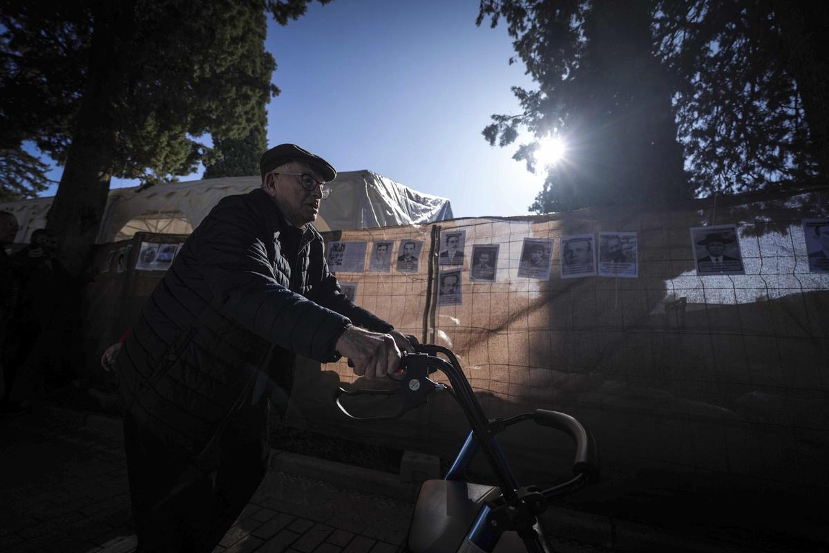 Un hombre pasa en bicicleta frente a las fotos colocadas.