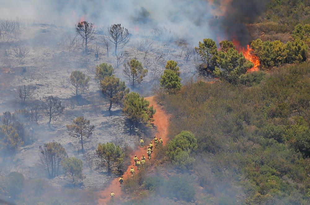 Firefighters climb a mountain to extinguish a ...