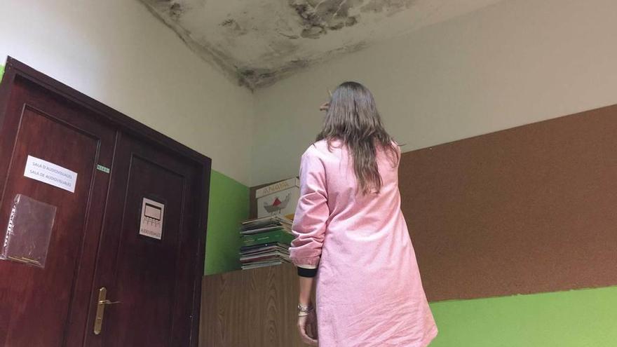 Una docente, ayer, señalando las manchas de humedad que se filtran por el tejado del edificio de Primaria del colegio de Infiesto.