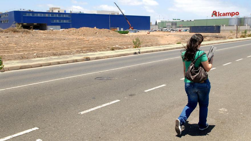 Una joven camina en el parque comercial de La Mareta. Al frente, los terrenos de la discordia.