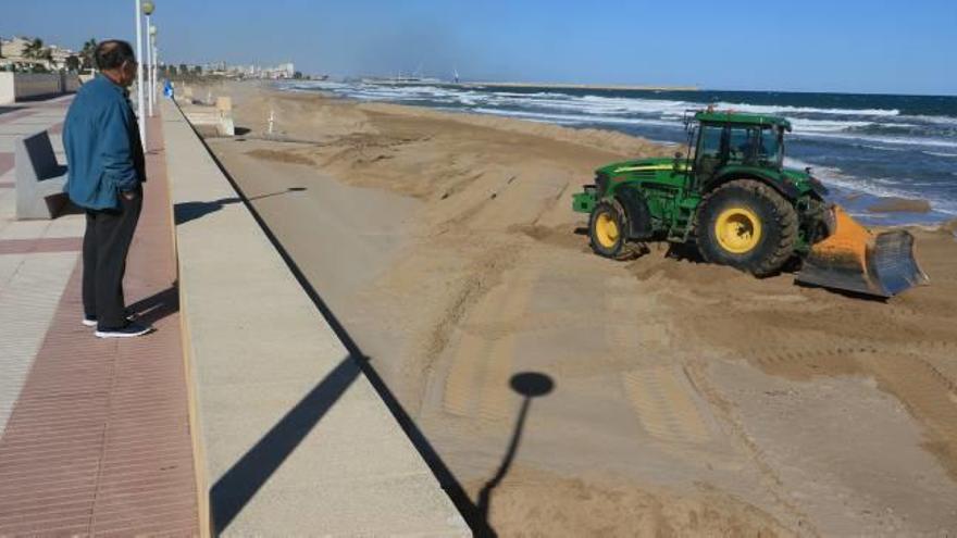 Un hombre observa, desde el paseo marítimo, los trabajos de una de las máquinas en la playa de Daimús, ayer.