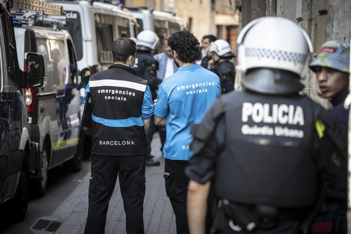 Dos técnicos del CUESB esperan frente a un desahucio en la calle Hospital preveyendo que puede haber personas en situación de exclusión social que necesiten un alojamiento o asistencia de urgencia.